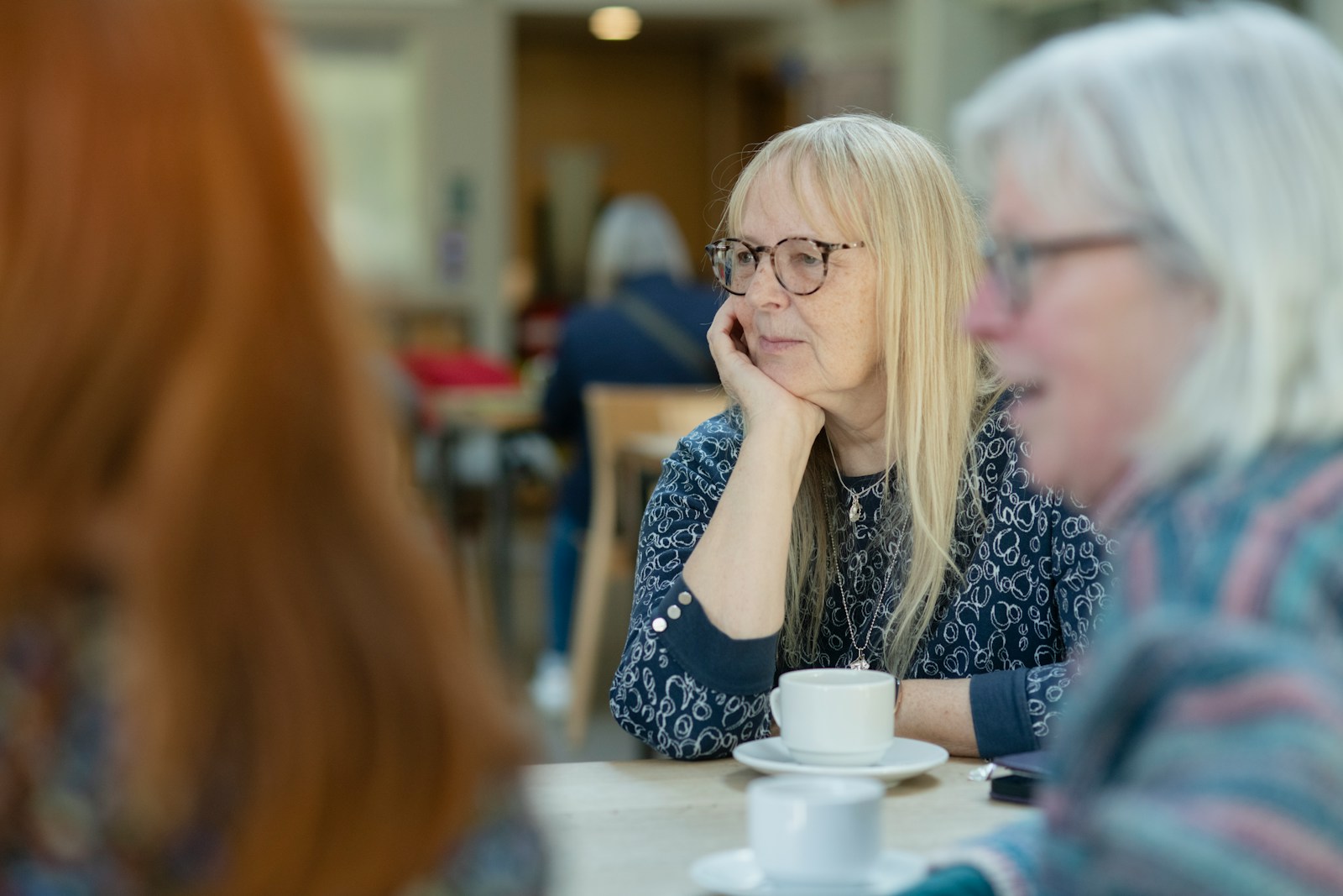 a woman sitting at a table with a cup of coffee