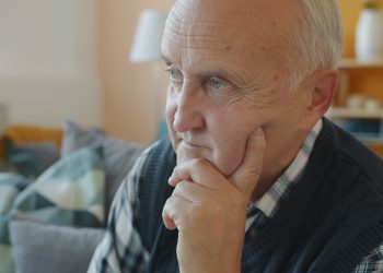 Elderly man with hand on chin, deep in thought.